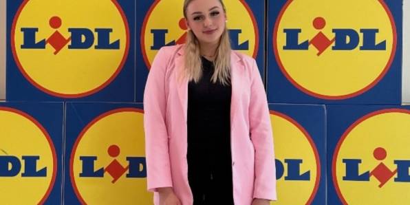 Azubine Elisabeth vor einer Wand mit Lidl Logos