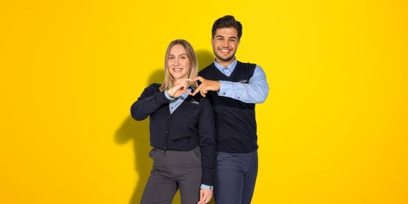 Zwei Filialleiter machen ein Herz mit ihren Fingern.
