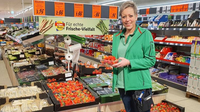 Mitarbeiterin Frischebeauftragte vor Obst und Gemüse