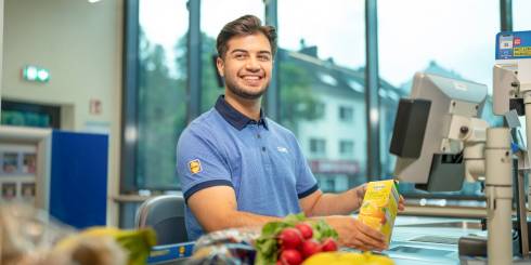 Der Duale Student sitzt an der Kasse.