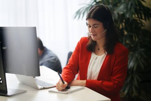 Mitarbeiterin arbeitet mit Headset am Computer