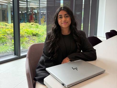Trisha sitzt mit dem Laptop im Büro.
