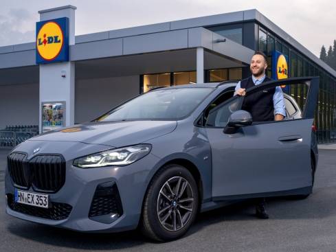 Filialleiter mit Auto vor Filiale.