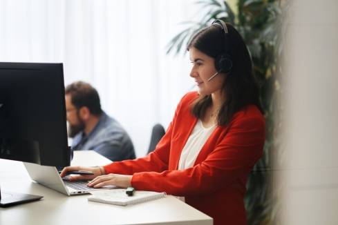 Mitarbeiterin arbeitet mit Headset am Computer