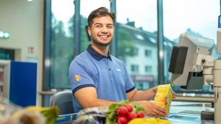 Der Duale Student sitzt an der Kasse.