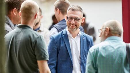 Abteilungsleiter für Onboarding- und Ausbildungskonzepte Amir steht in einer Gruppe Menschen.